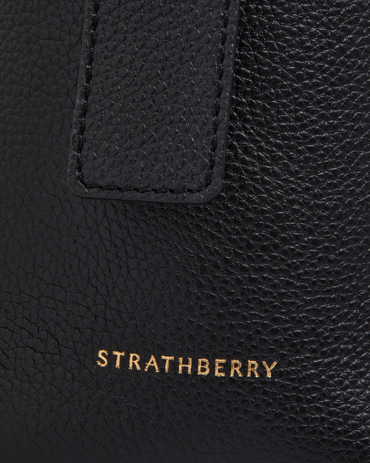 Black pebbled leather Kite Hobo showing strap and gold Strathberry logo.
