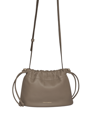 Strathberry taupe Charlotte drawstring bag with long adjustable strap and front logo.