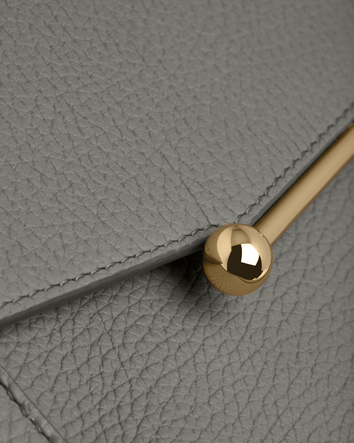 Stone grey pebbled leather mosaic bag flap with gold bar and spherical clasp.