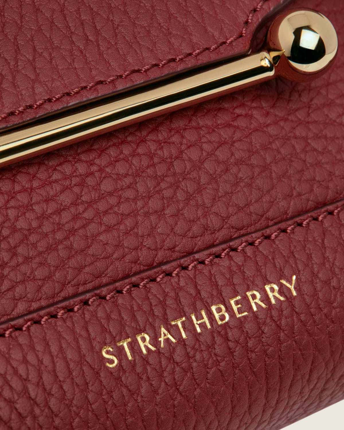 Strathberry Mosaic Nano in oxblood textured leather with gold bar closure
