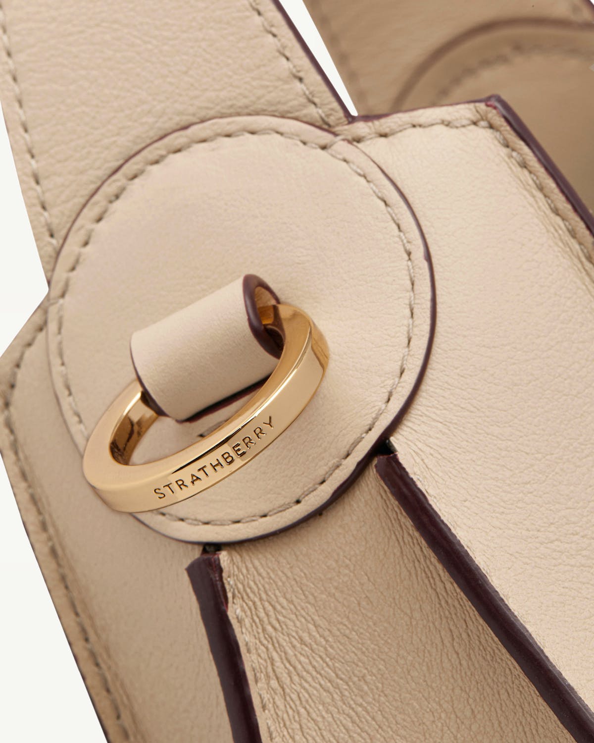 Close-up of Strathberry Arkshell oat leather bag front ring closure.