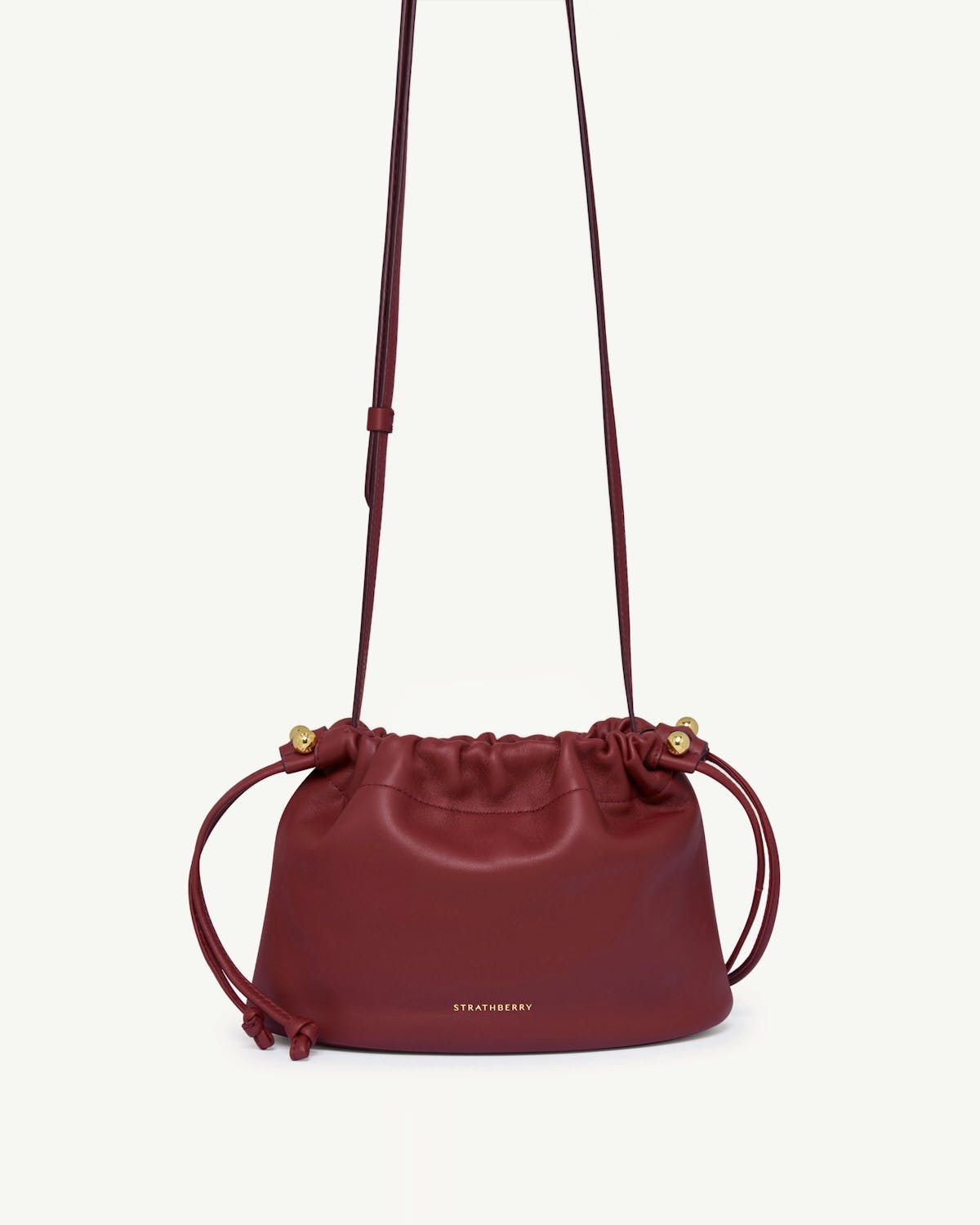 Oxblood Strathberry Charlotte drawstring bag with long strap and gold fittings.