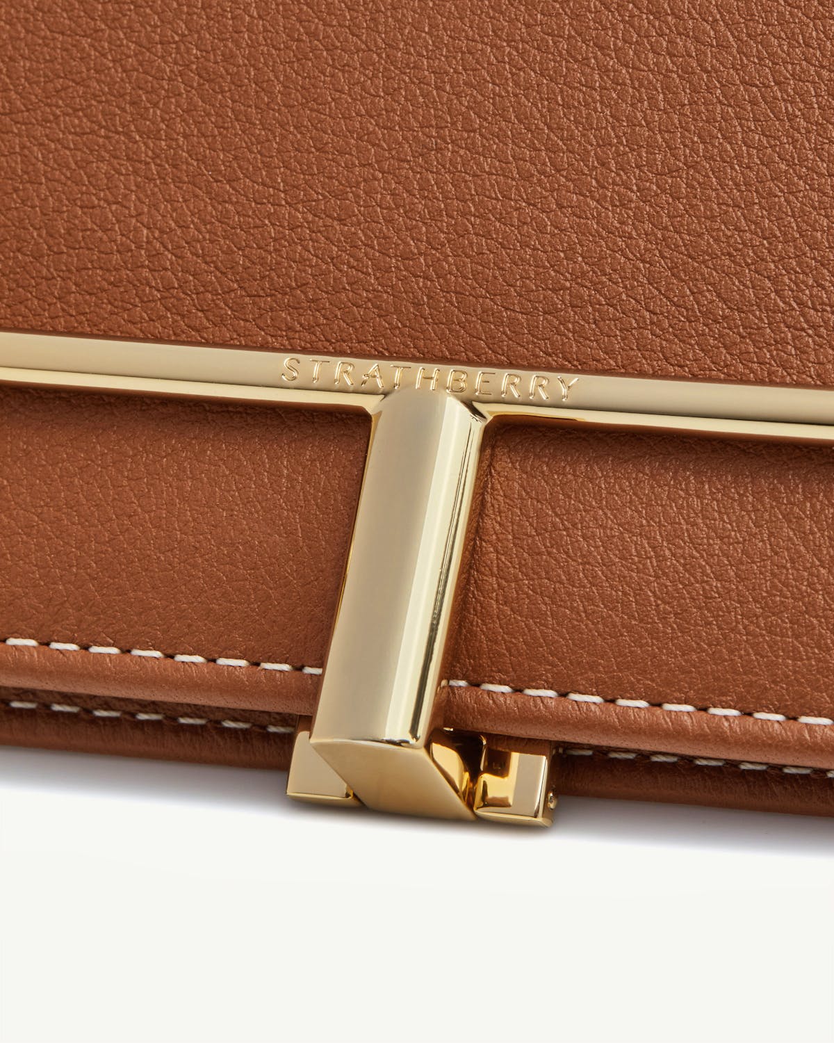 Chestnut leather wallet clasp with gold Strathberry bar and vanilla stitching.