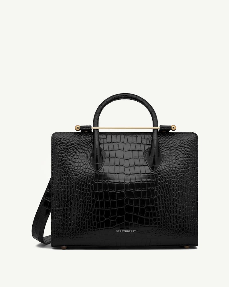 Strathberry midi tote in black croc-embossed leather with top handles, shoulder strap and gold bar