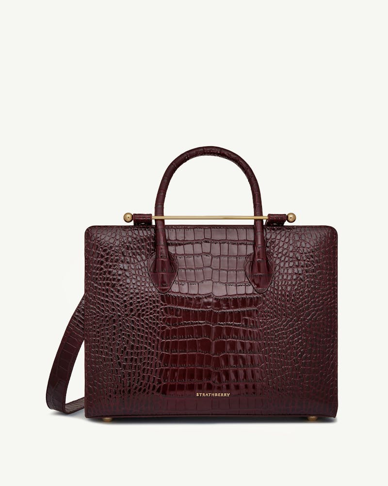 Burgundy croc-embossed leather midi tote with top handles, shoulder strap and Strathberry logo.