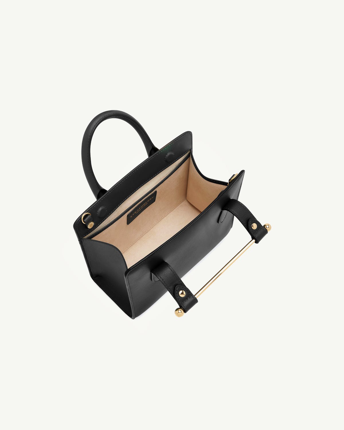 Strathberry black mini tote with open top showing beige interior and gold bar