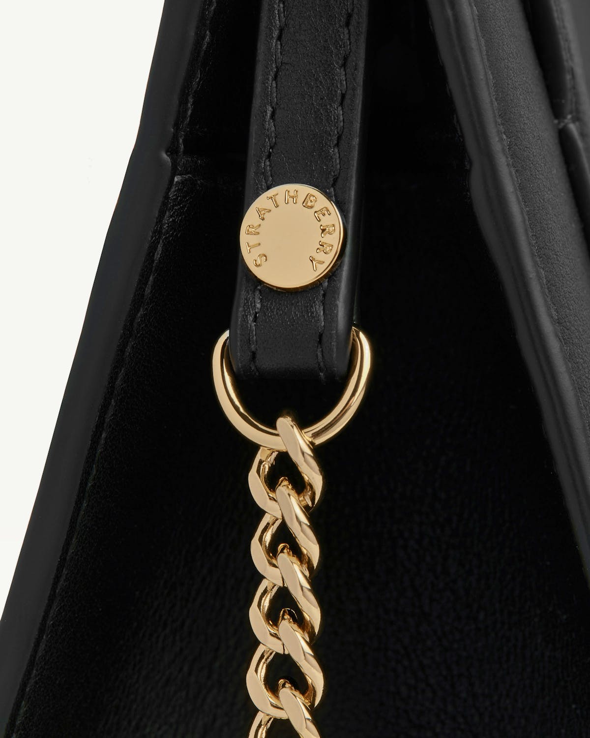 Strathberry black mini tote side with gold chain and logo button