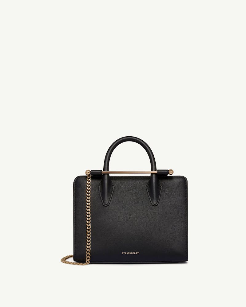 Strathberry black mini tote with top handles and gold chain strap.
