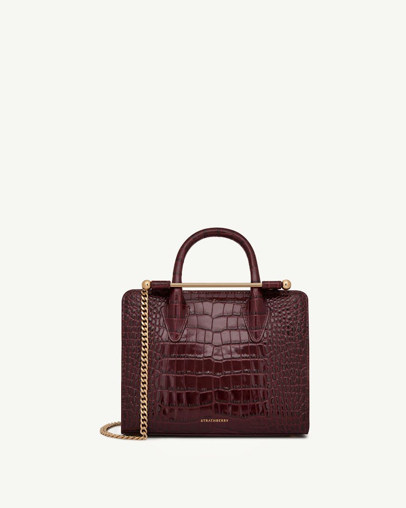 Strathberry mini tote in burgundy croc with gold bar and chain.