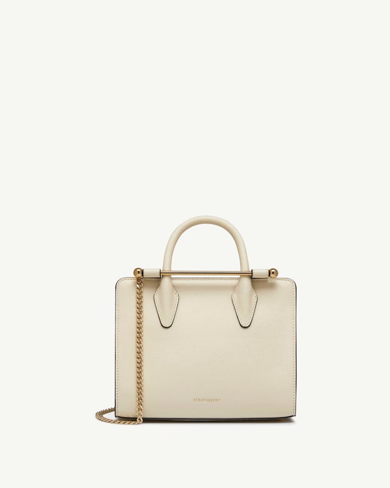Strathberry vanilla mini tote with top handle and gold chain strap.
