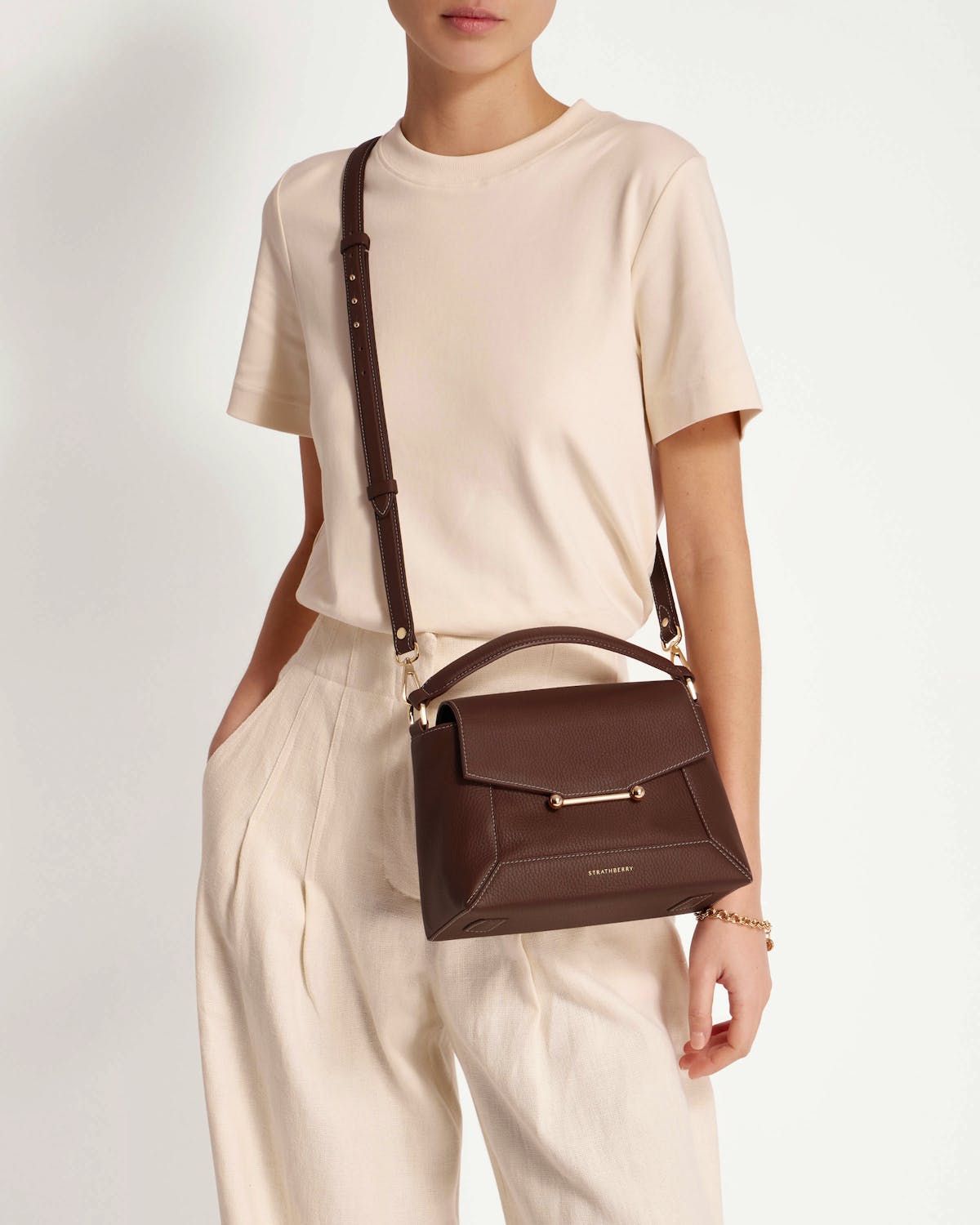 Woman wearing Strathberry mosaic bag in chocolate with vanilla stitch crossbody