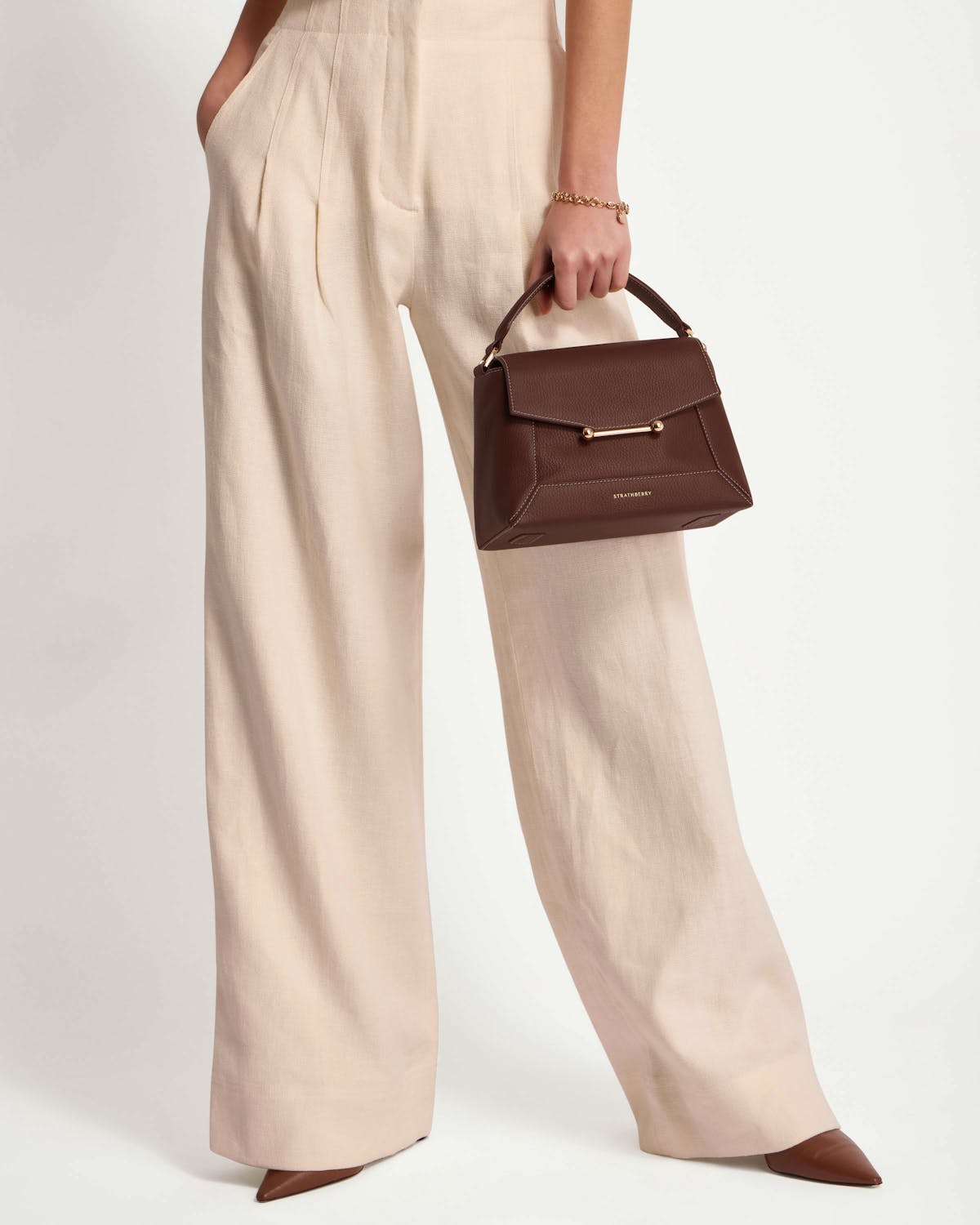Strathberry Mosaic top-handle bag in chocolate with vanilla stitch handheld at hip