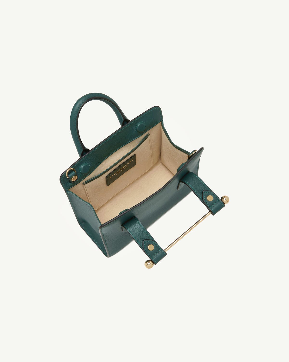 Bottle green Strathberry nano tote open, showing beige interior and gold bar