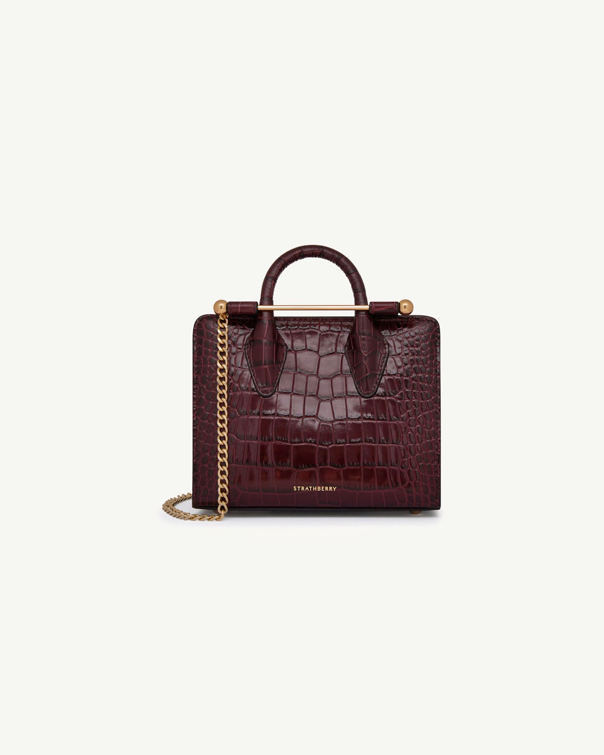 Strathberry croc-embossed nano tote in burgundy with gold bar and chain strap.