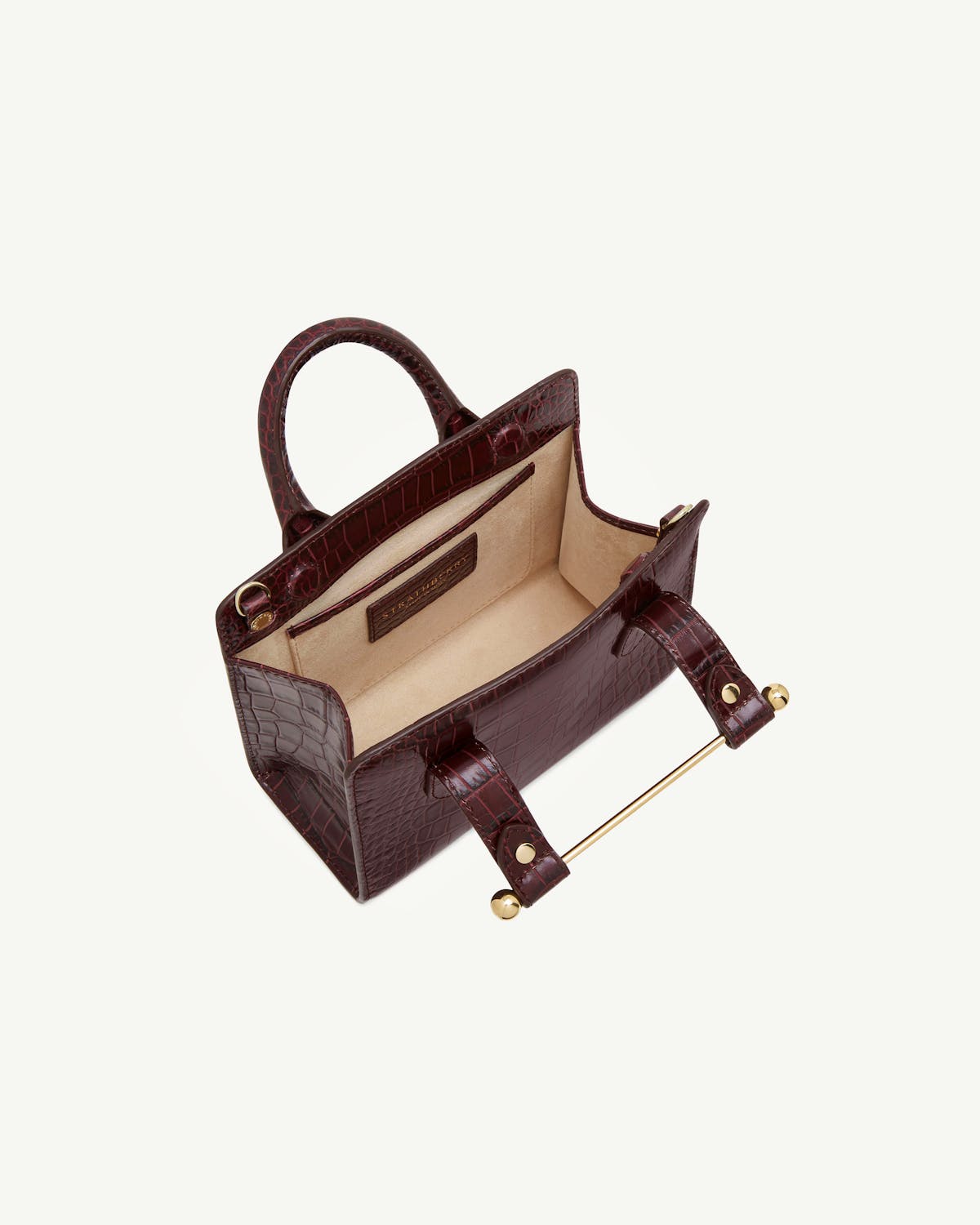 Croc-embossed nano tote with top handles and beige lining, open interior.