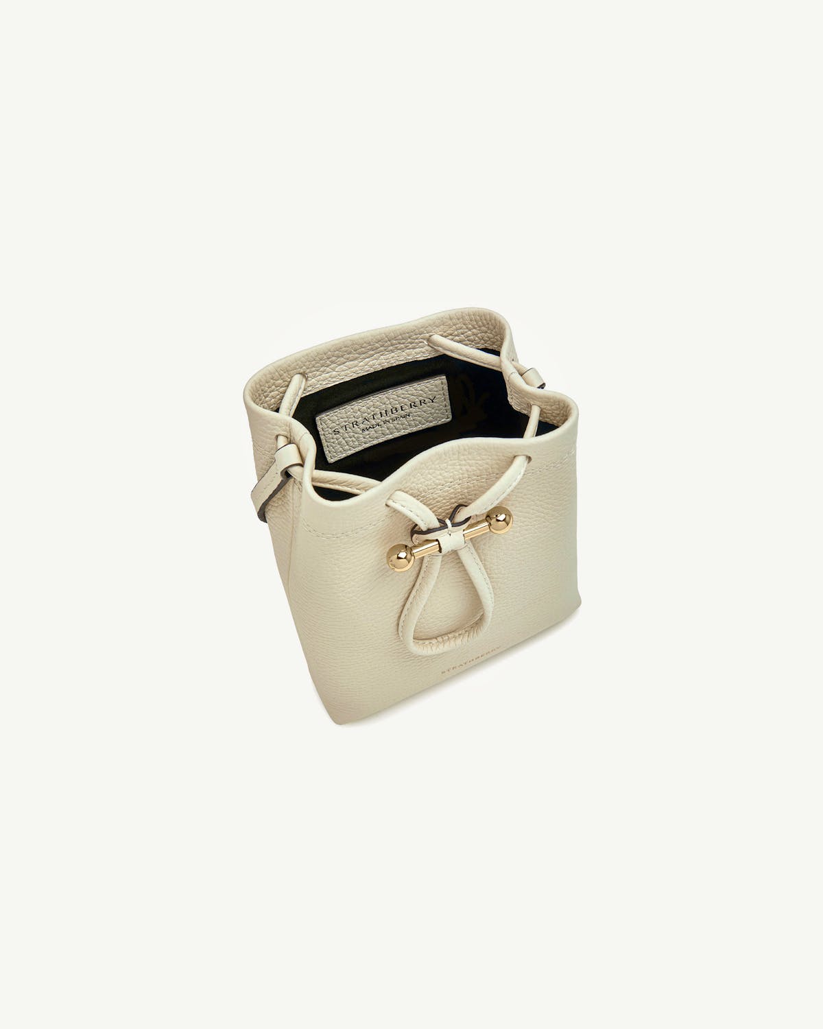 Strathberry Osette midi pouch in vanilla pebbled leather with gold bar closure.