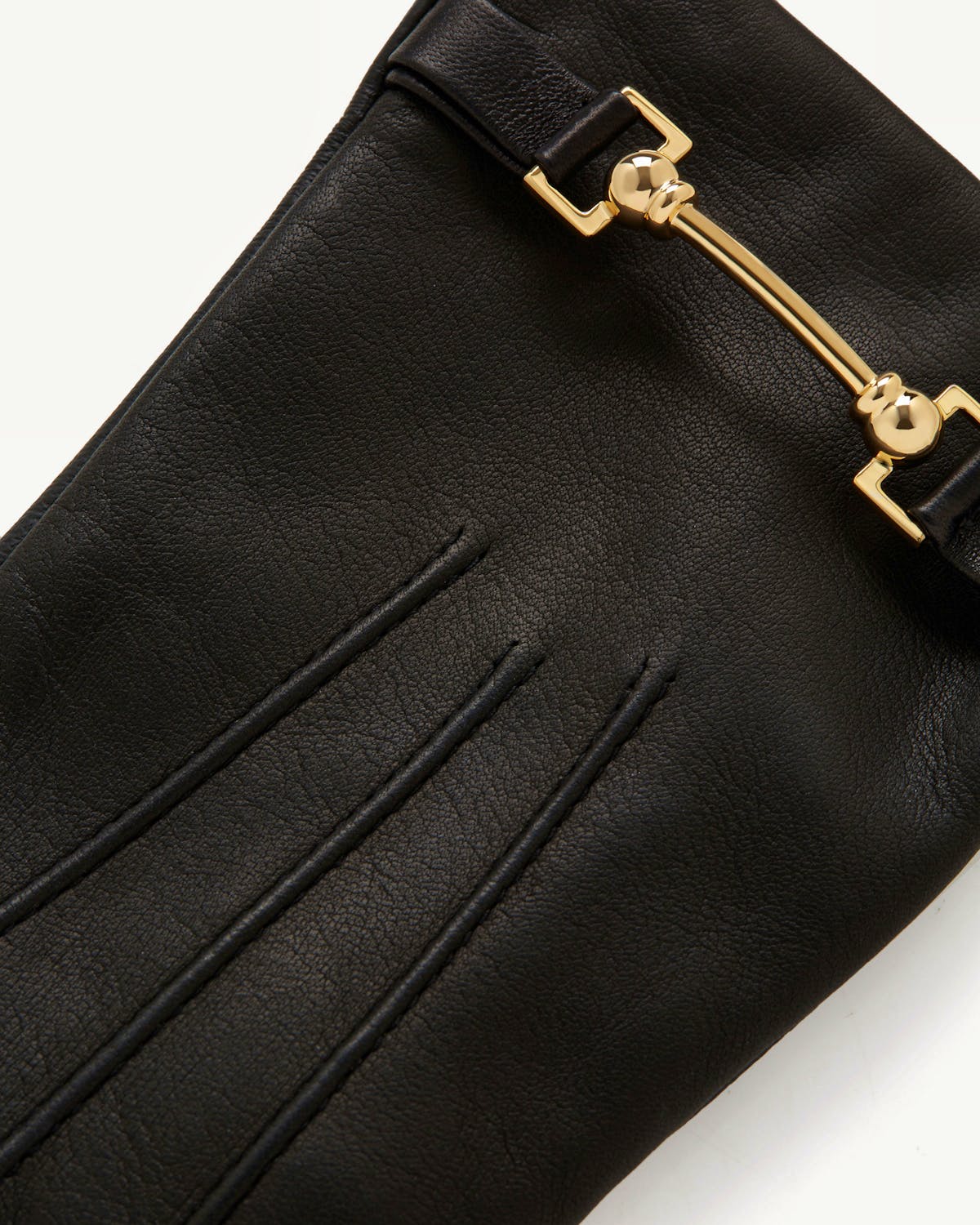 Black leather glove with gold metal bar hardware and three stitched decorative seams.
