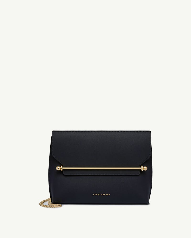 Strathberry black Stylist bag with gold bar closure and chain strap on white