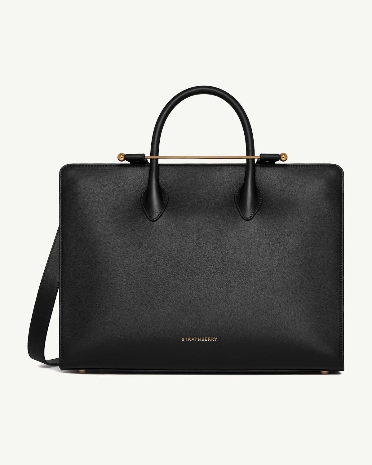 Black Strathberry leather tote with top handles, shoulder strap, and gold bar detail.