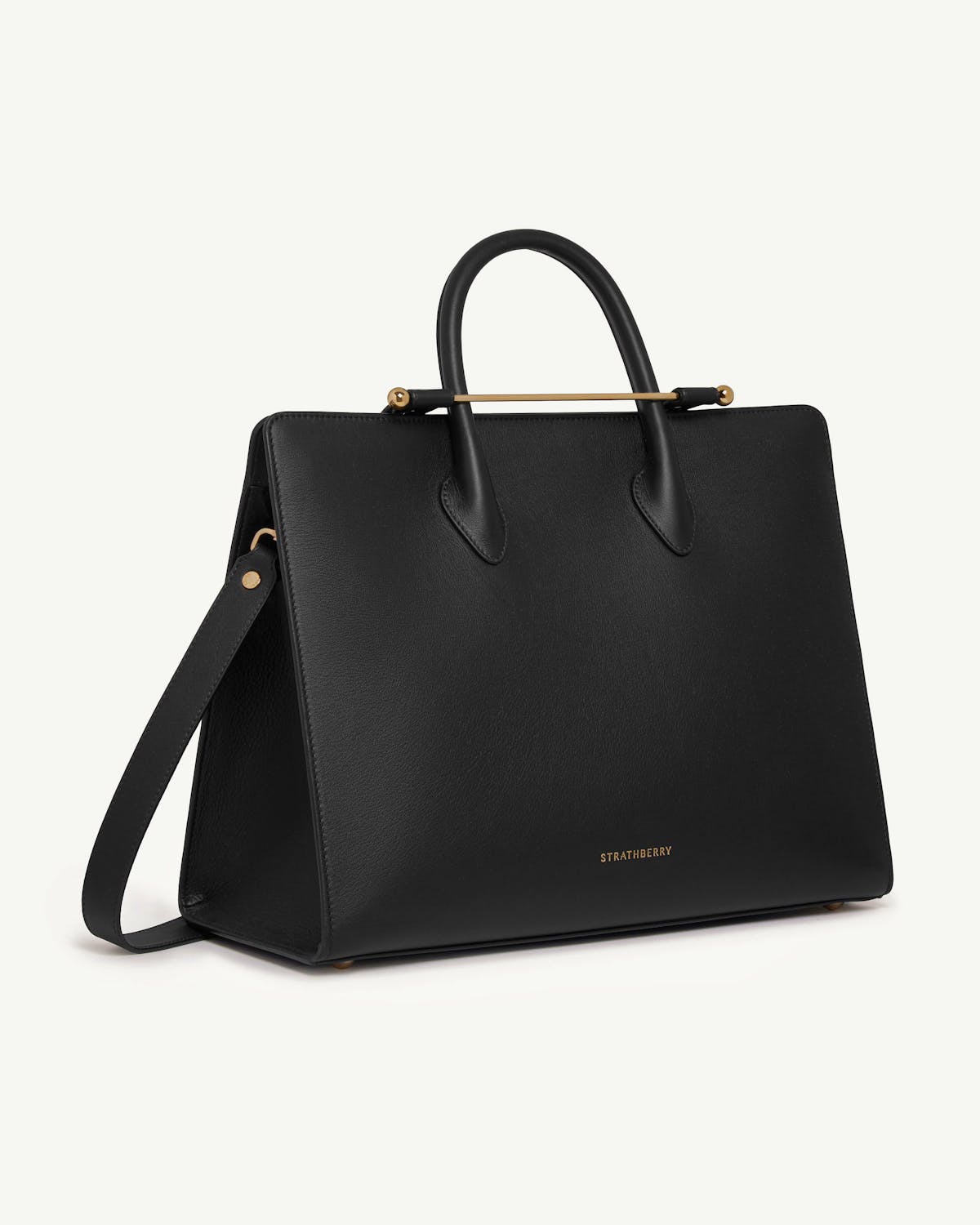 Black Strathberry leather tote with top handles, shoulder strap and gold bar.