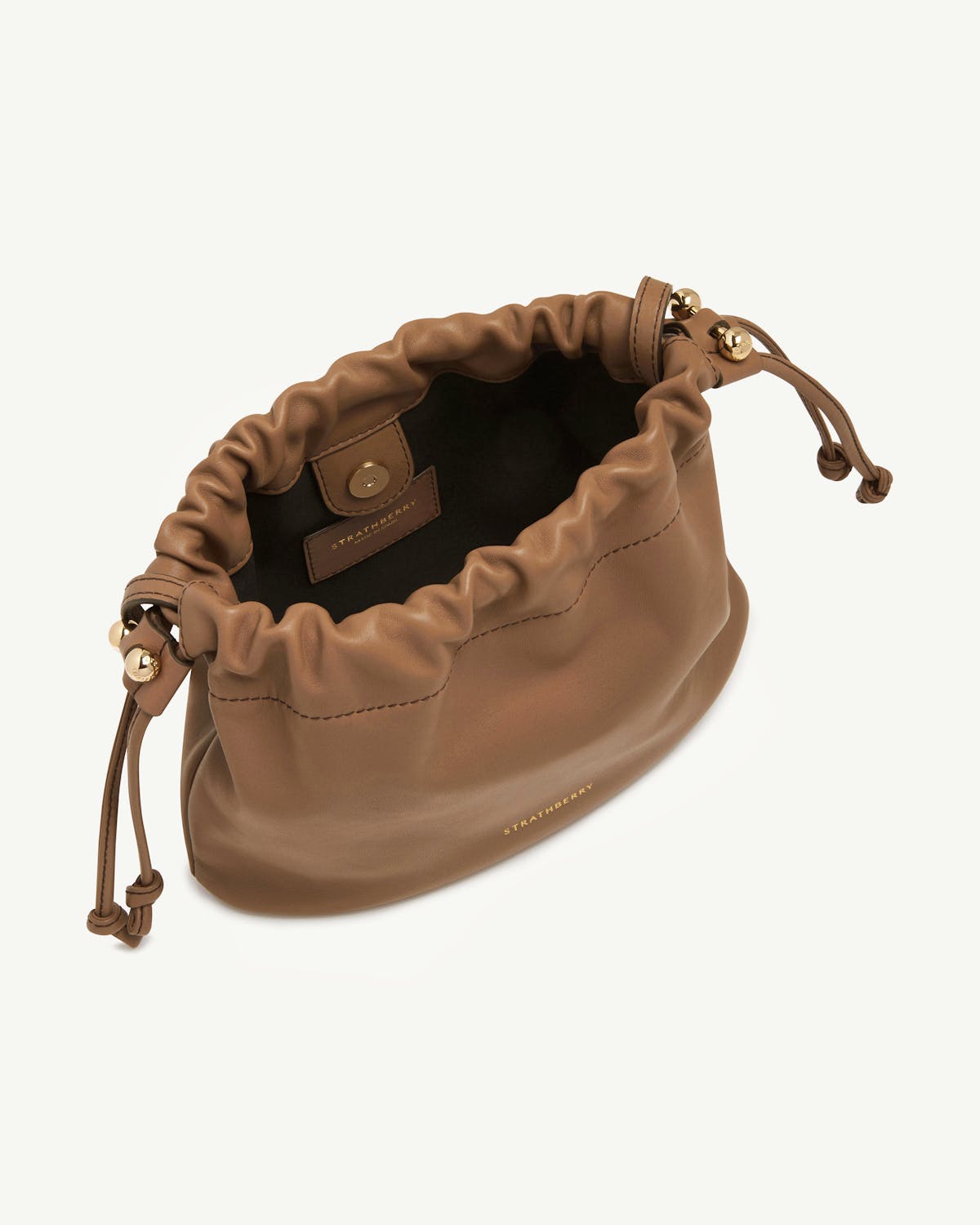 Strathberry Charlotte drawstring bag in clay leather, open with gold beads and black interior