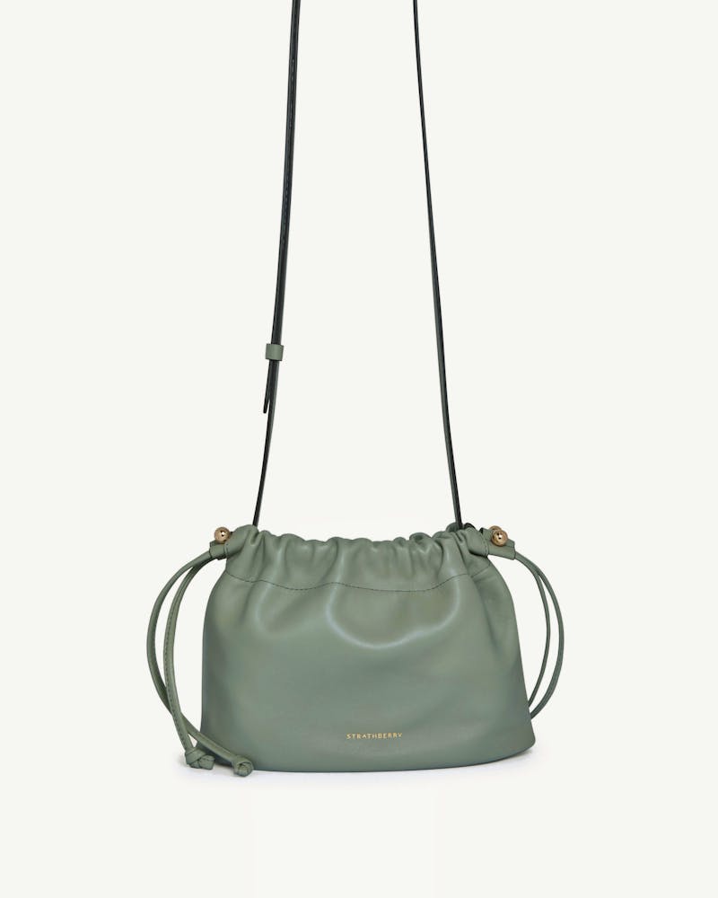 Strathberry Charlotte drawstring bag in library green with long shoulder strap.