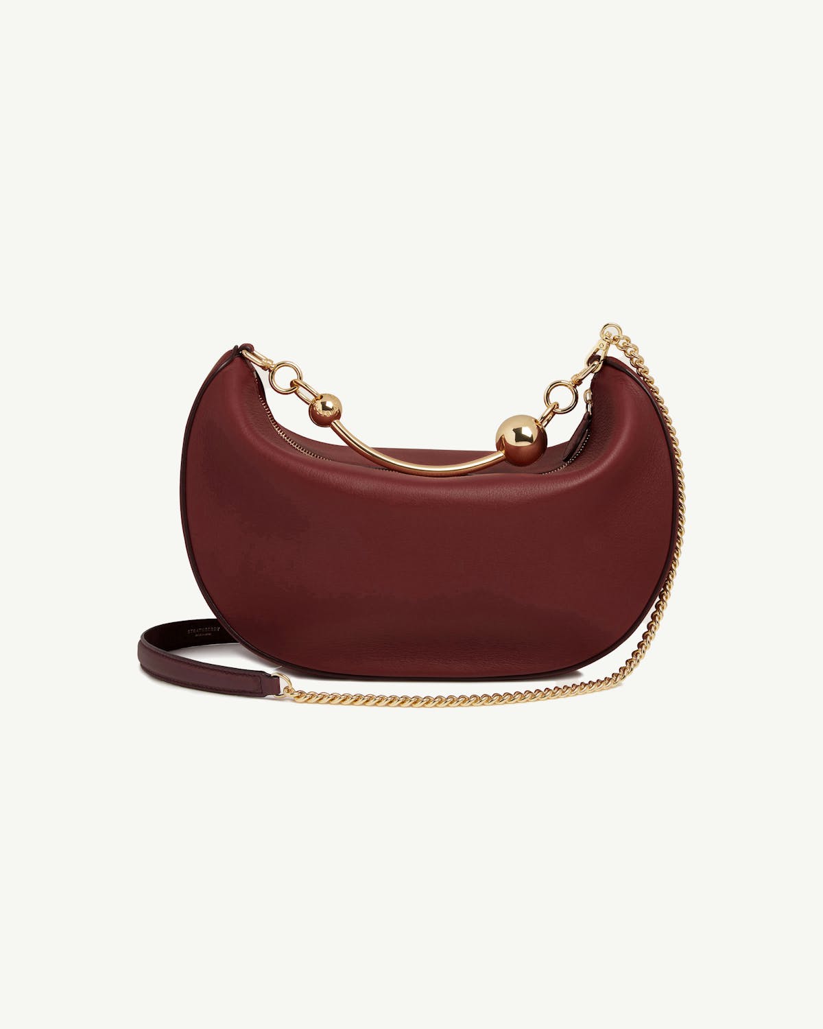 Oxblood crescent-shaped leather shoulder bag with gold chain and sphere accents.