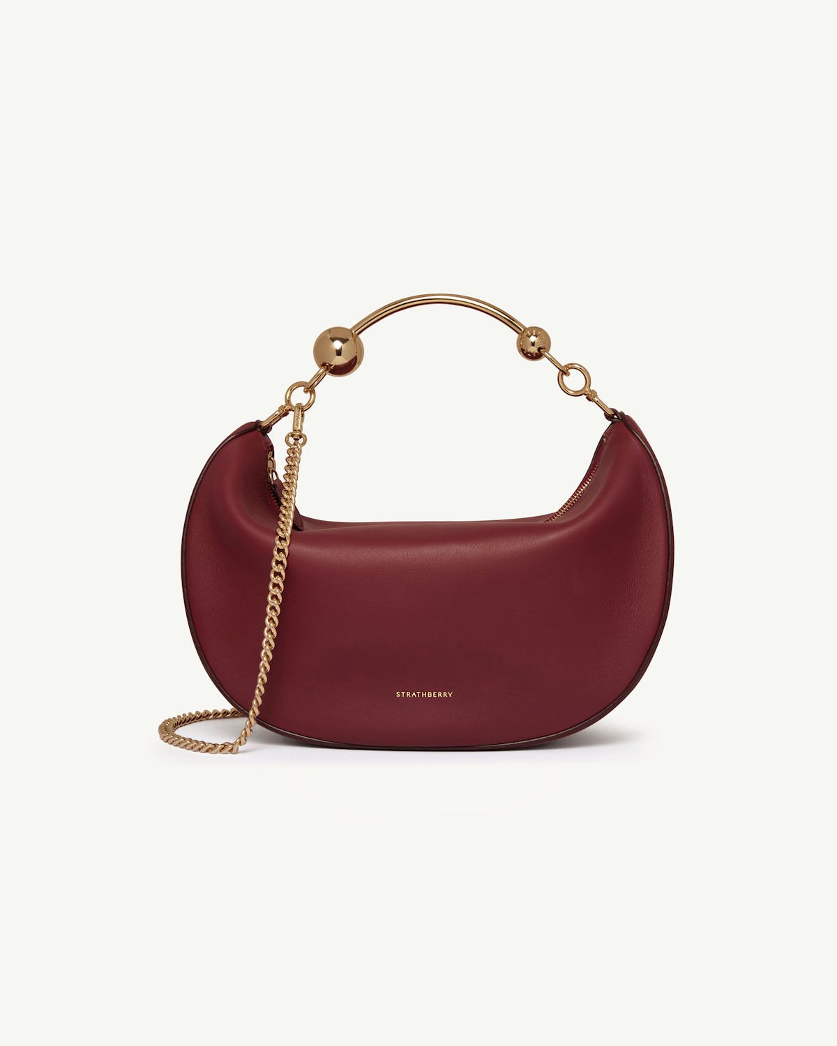 Oxblood crescent moon bag with gold chain, curved metal handle and Strathberry logo