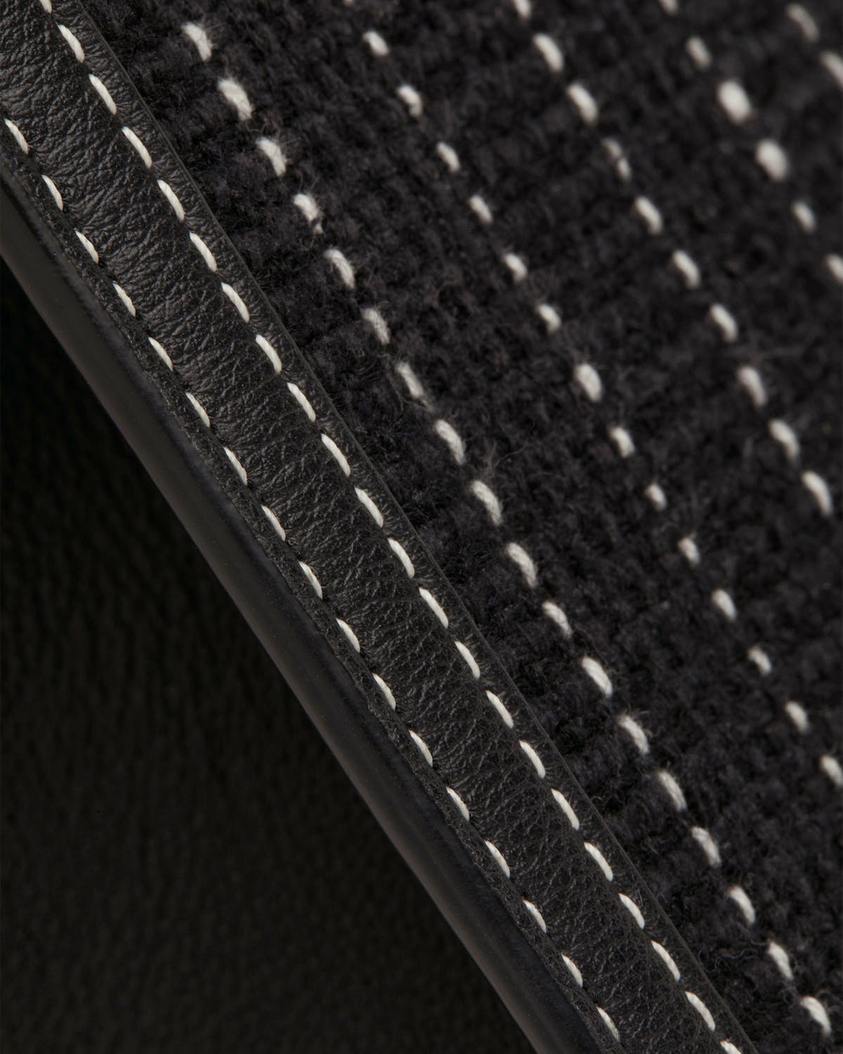 Close-up of black tweed mini tote with leather trim and white topstitching