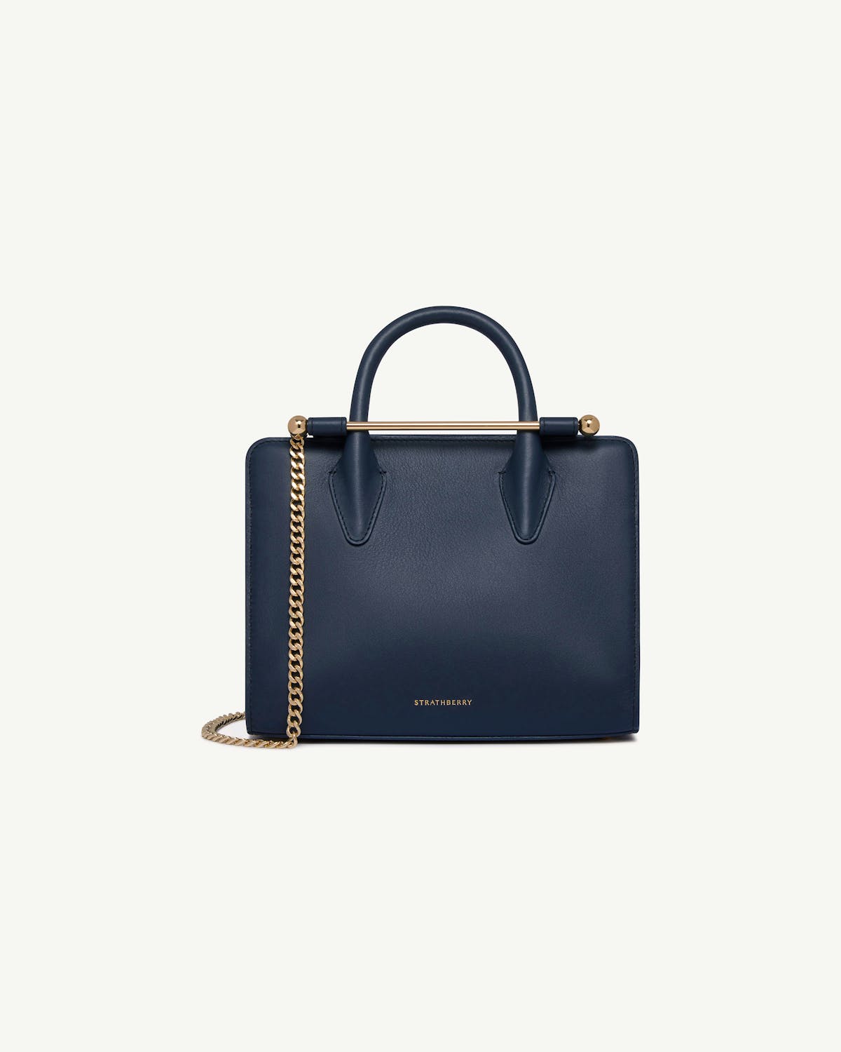 Strathberry marine blue mini tote with top handles and gold chain strap.