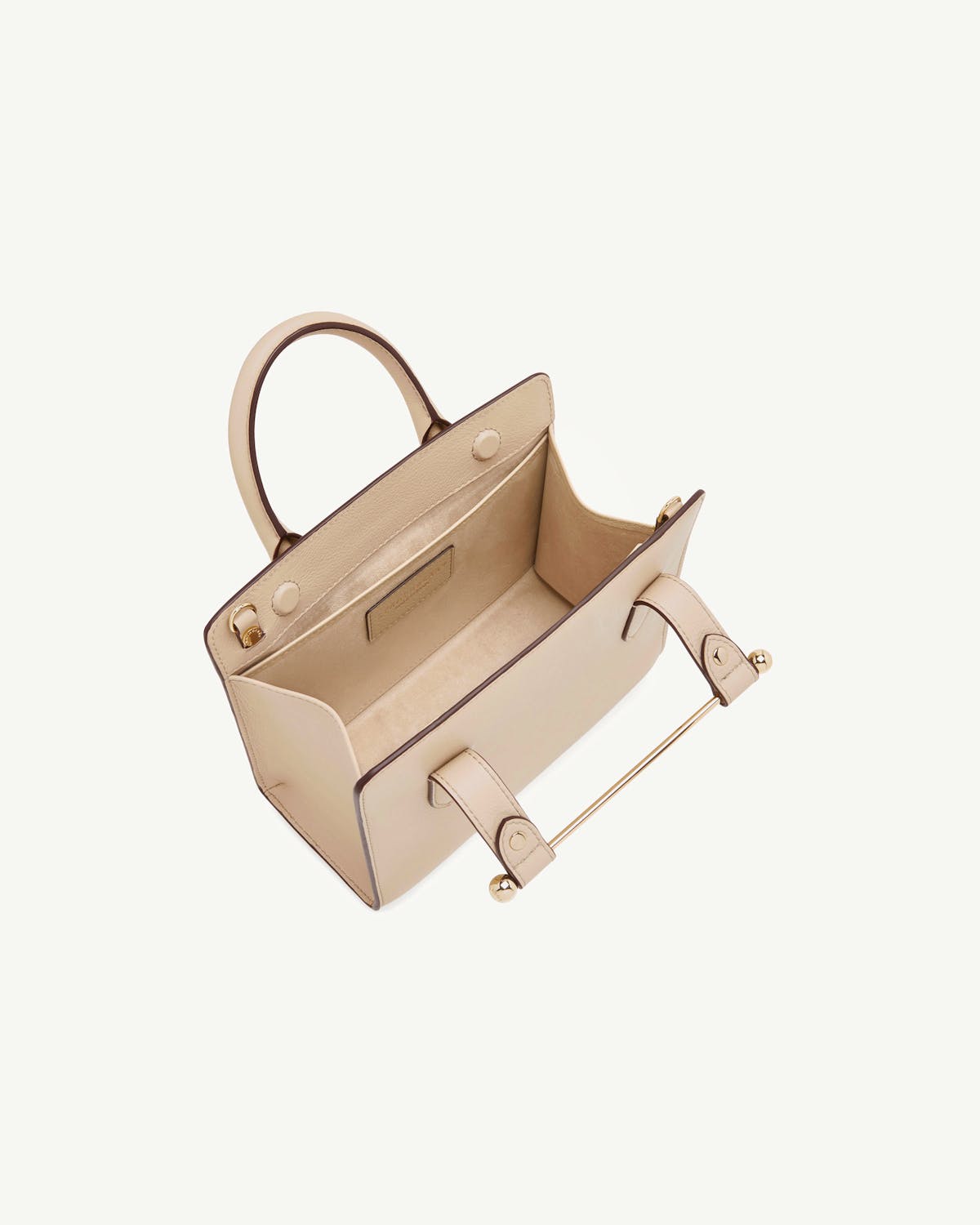 Mini tote in oat with top handle, open interior and gold bar detail.