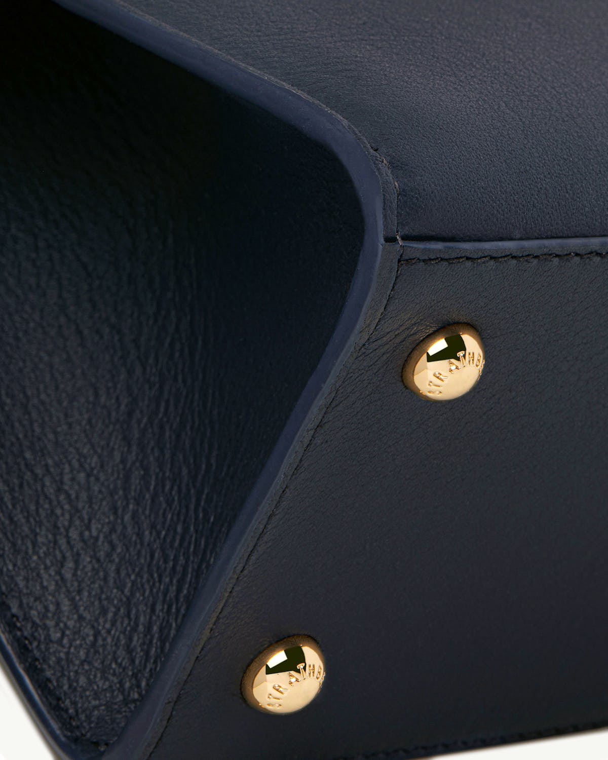 Close-up of marine blue Strathberry mini tote corner with gold studs
