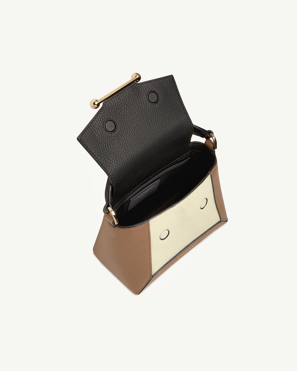Small clay, black and white leather bag with open black flap and gold bar closure.