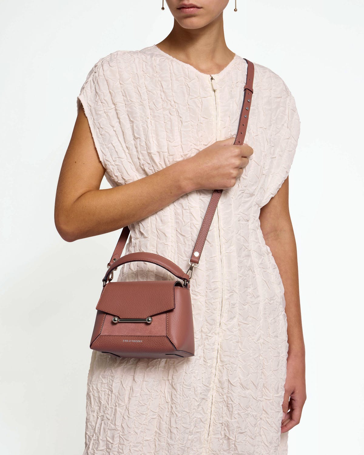 Model wearing Strathberry Mosaic Nano sienna dusty pink suede crossbody bag with top handle.