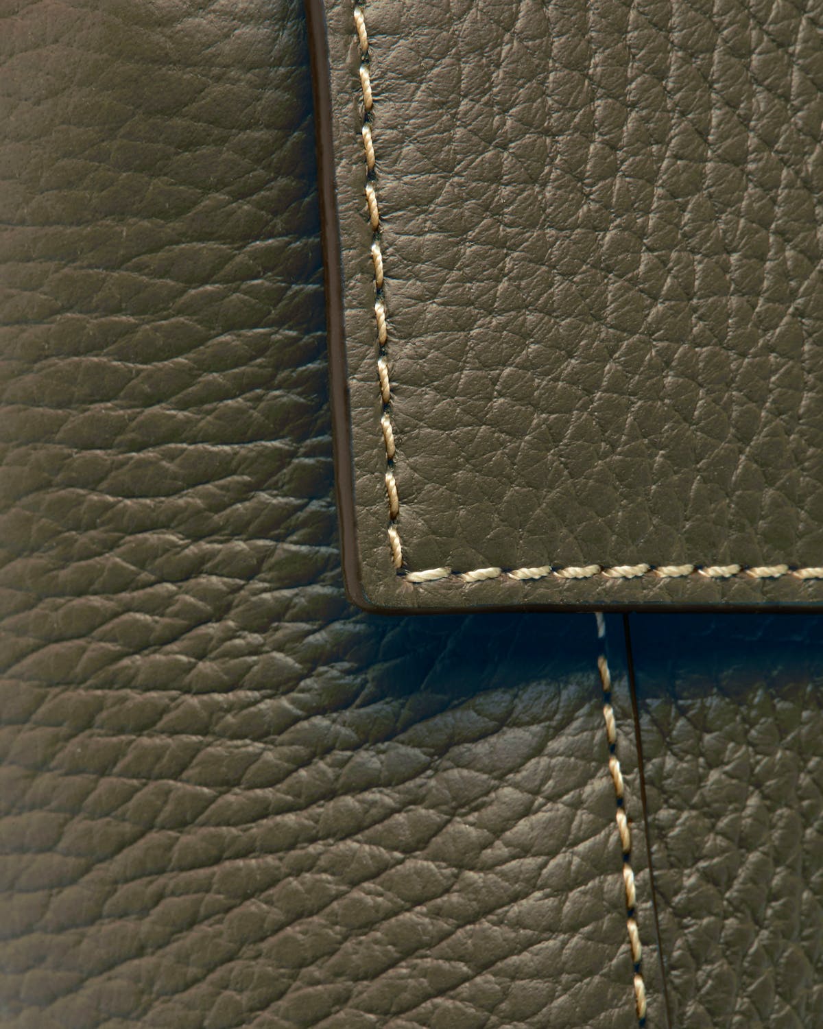 Khaki pebbled leather with contrast stitching on the bag flap edge.