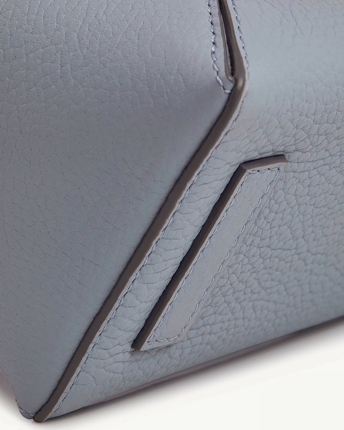 Close-up of dusky blue Mosaic Nano leather bag corner with stitching