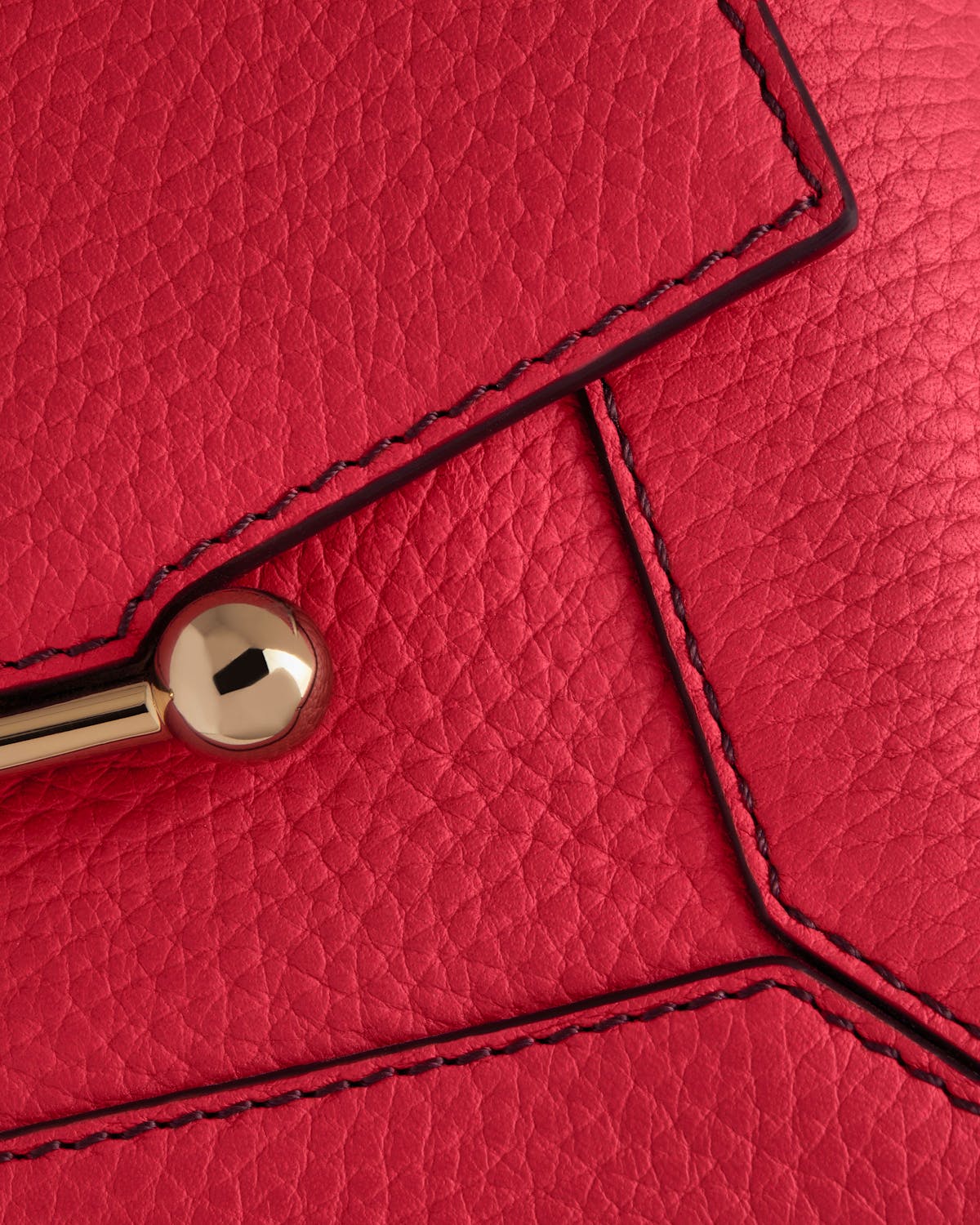 Close-up of raspberry leather Mosaic Nano bag with burgundy stitching and gold bar hardware