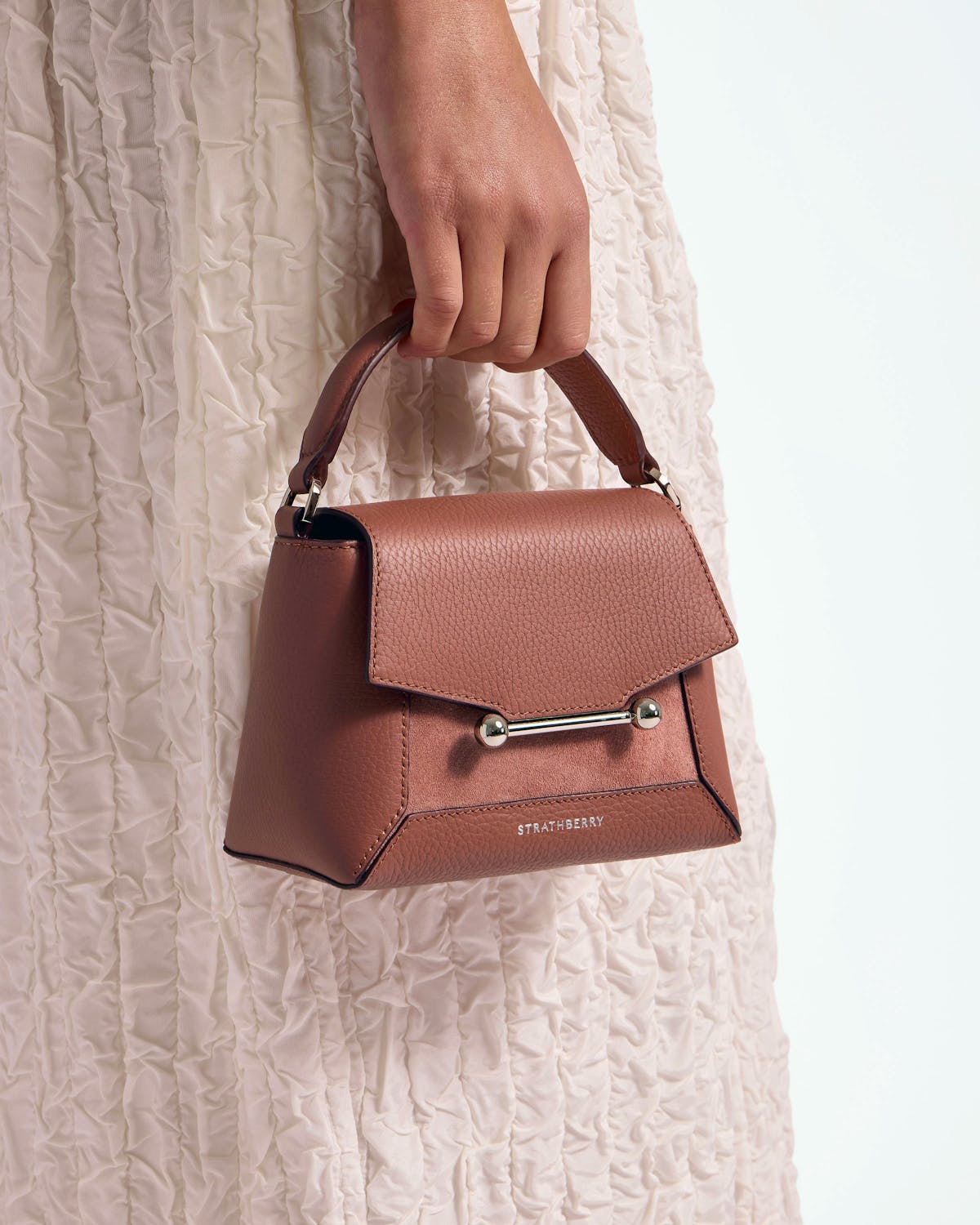 Hand holding Strathberry Mosaic Nano in sienna dusty pink suede with silver bar.