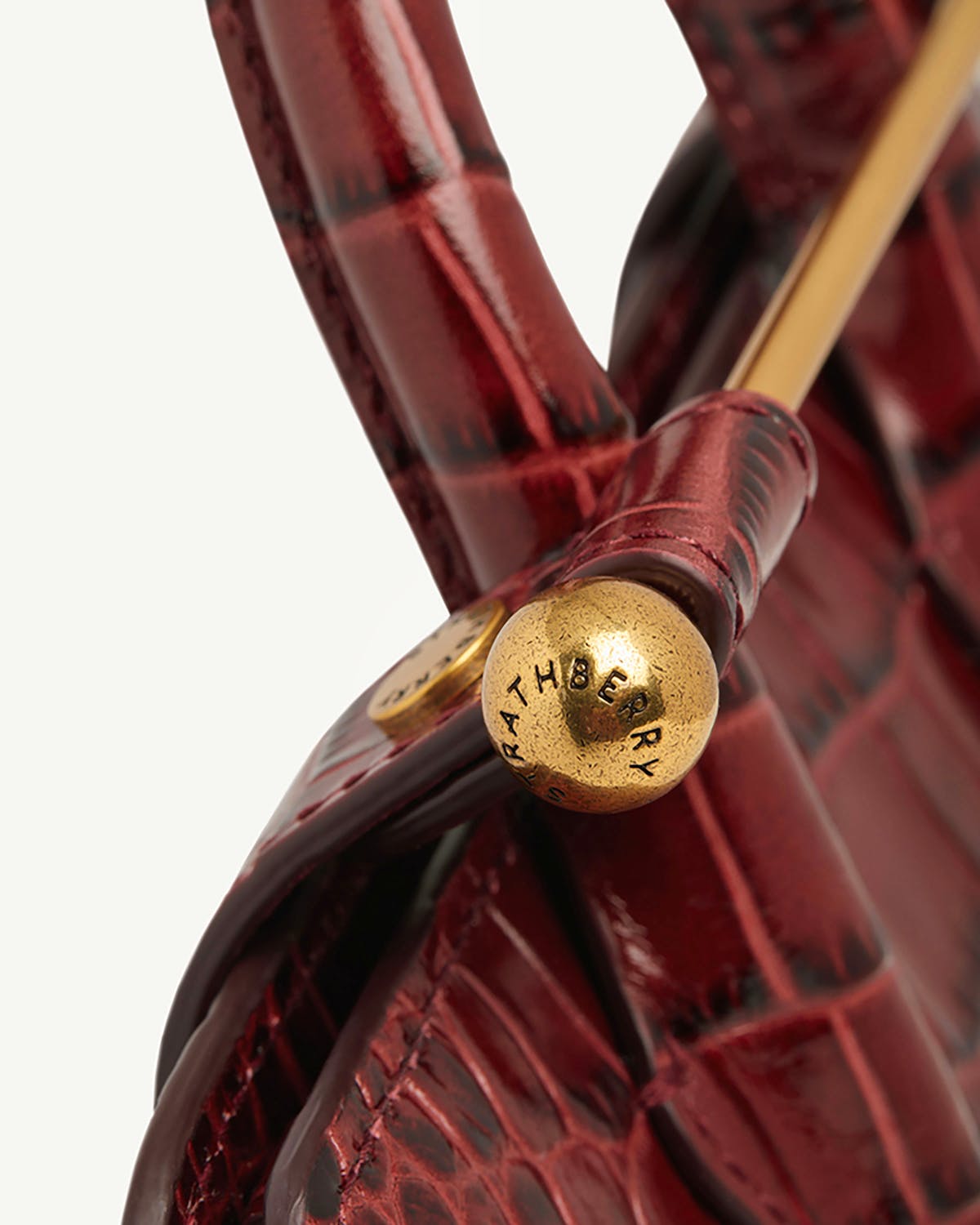 Strathberry croc-effect nano tote close-up of gold bar closure and handle