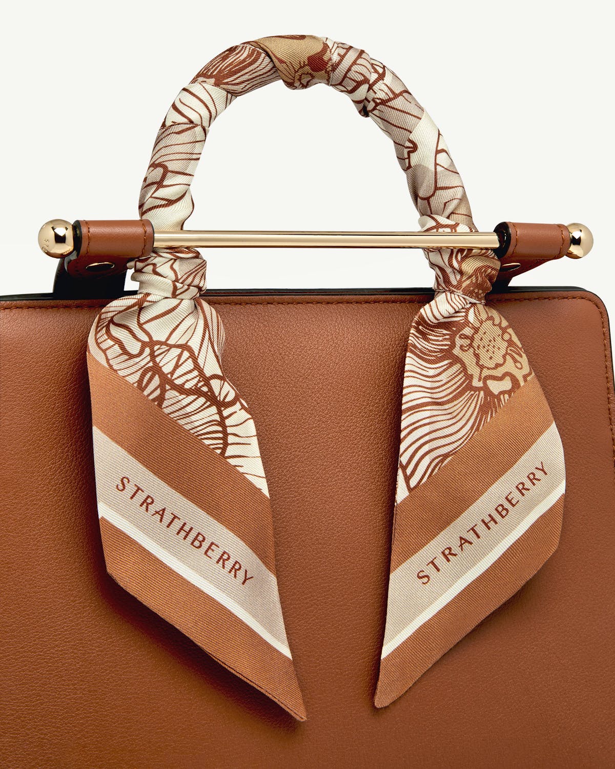 Floral chestnut and vanilla silk skinny scarf tied to leather bag handle, Strathberry.