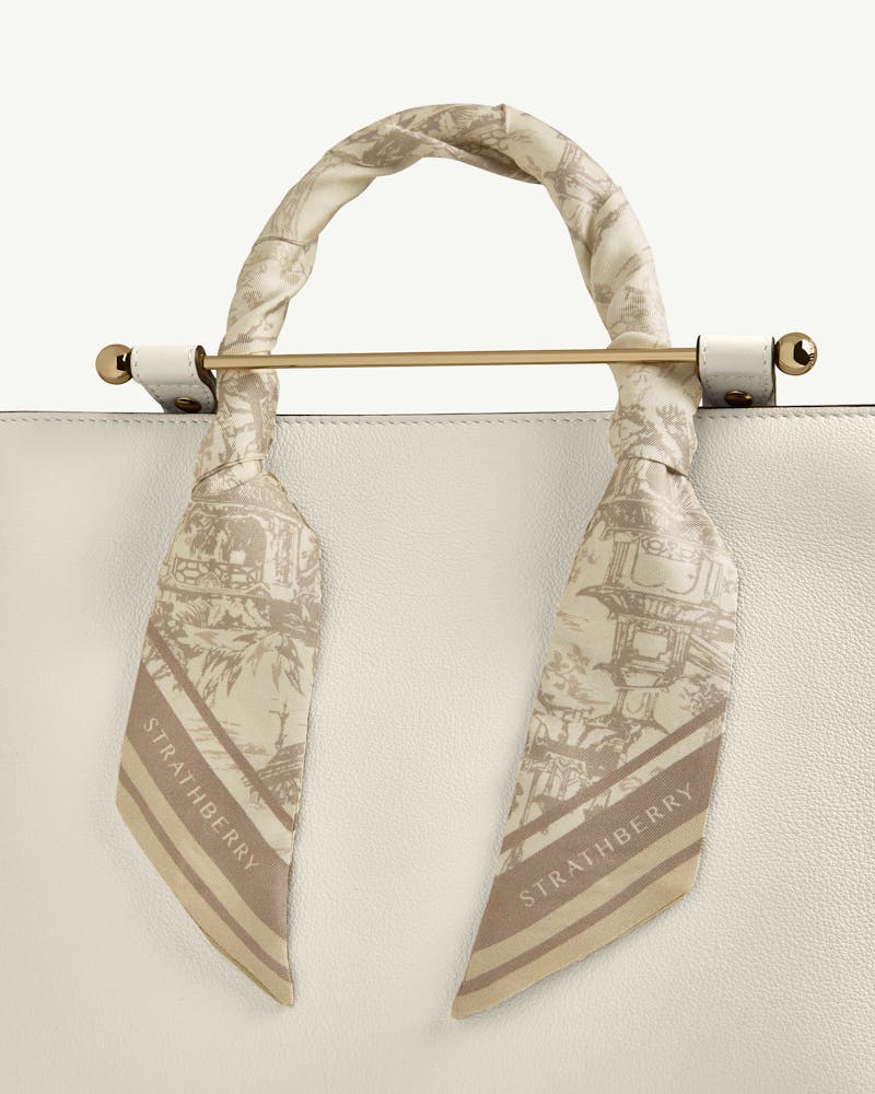 Strathberry silk skinny scarf in oat and mushroom oriental print, tied around handle.