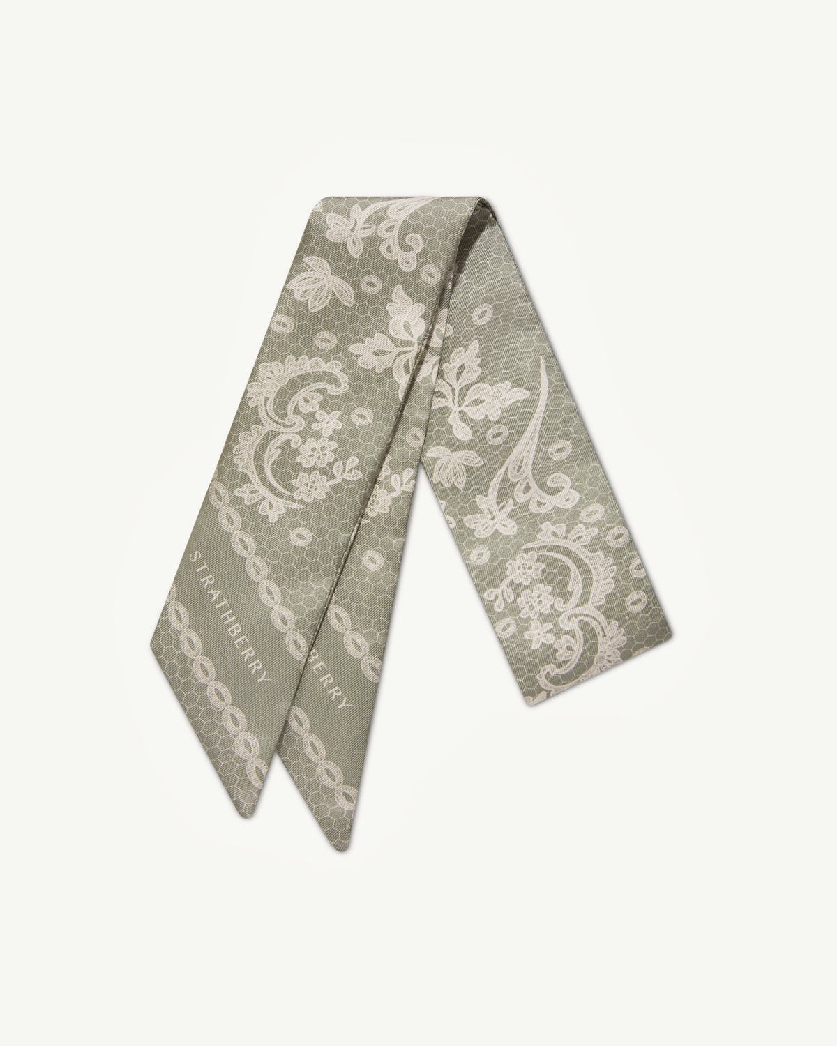 Sage silk skinny scarf with white lace print and visible Strathberry logo.