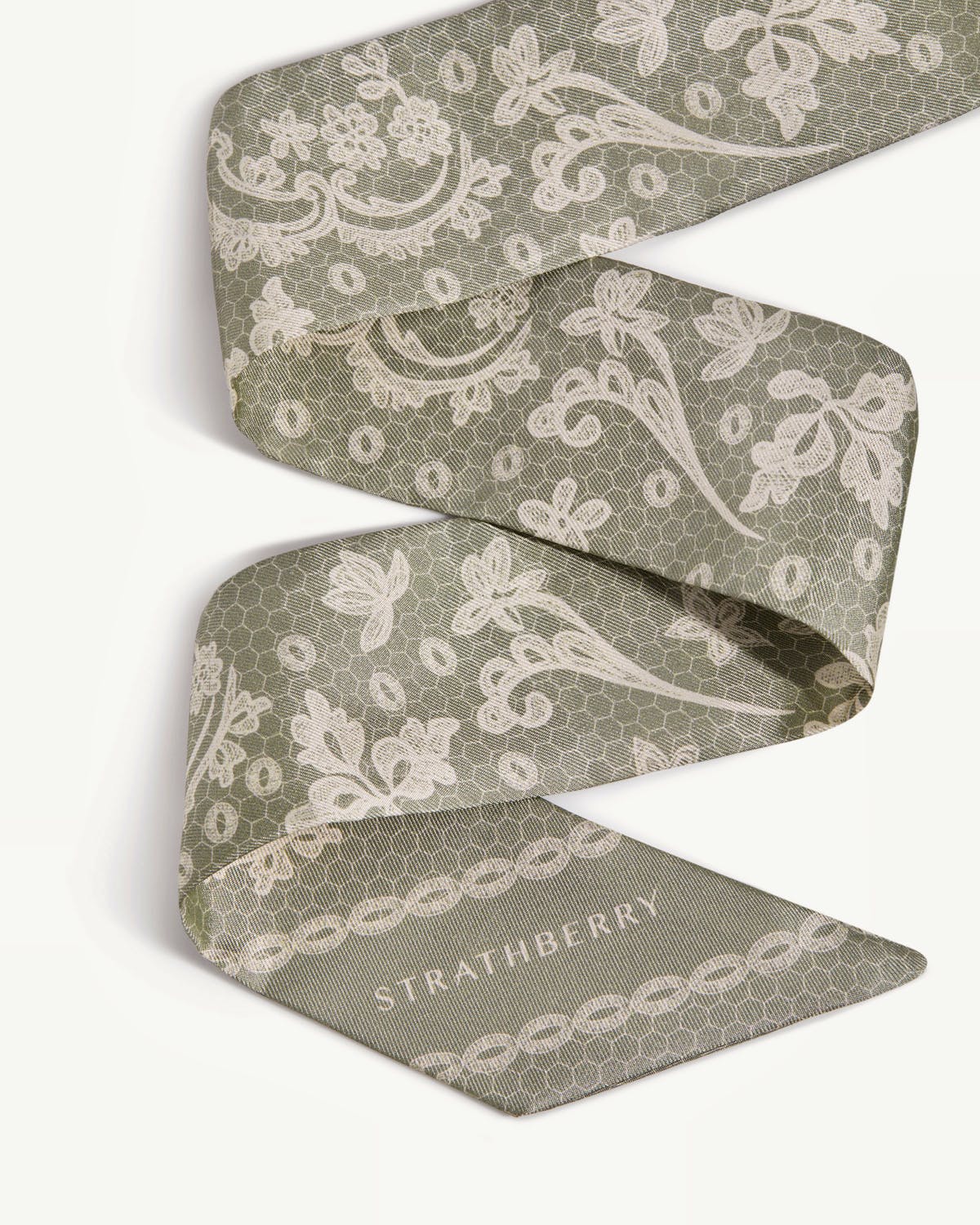 Sage silk skinny scarf with white lace print and visible Strathberry wordmark.