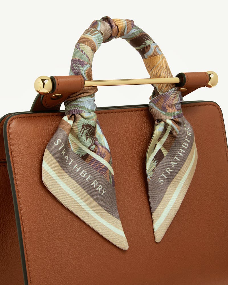 Silk skinny scarf in oat mushroom print tied to bag handle, Strathberry logo visible