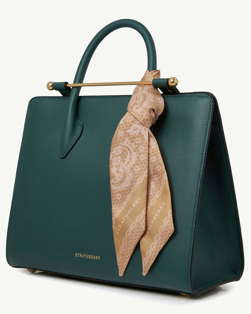 Rose lace silk skinny scarf tied to green Strathberry handbag, gold-tone hardware.