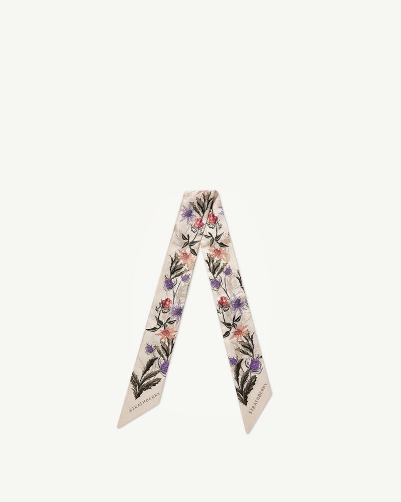 Strathberry vanilla silk skinny scarf with forest green thistle print, laid flat.