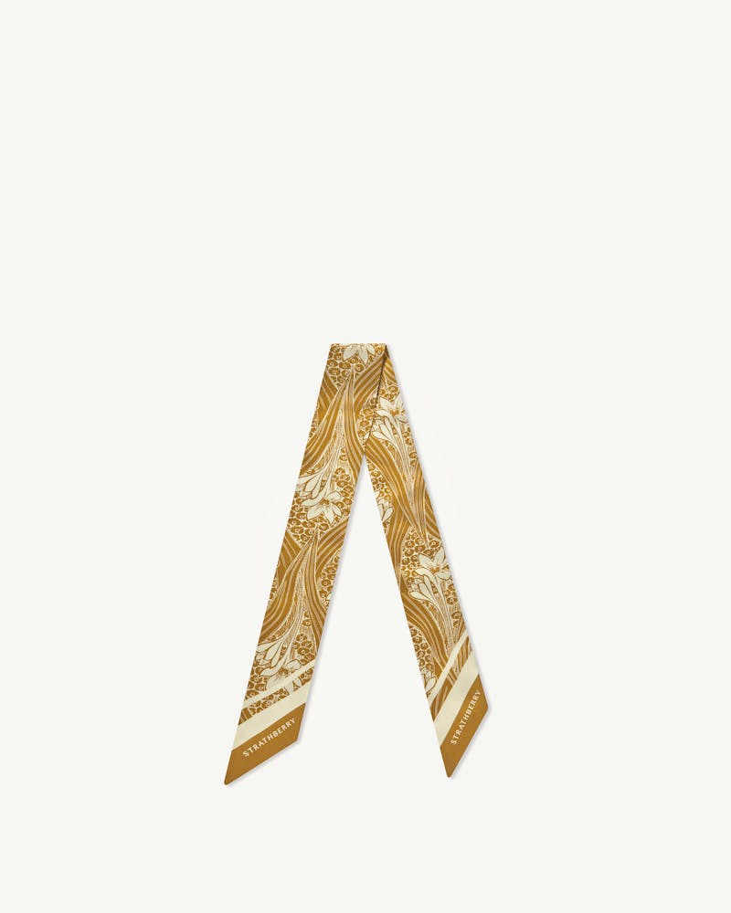 Strathberry mustard wallpaper-print silk skinny scarf folded into an inverted V on white.