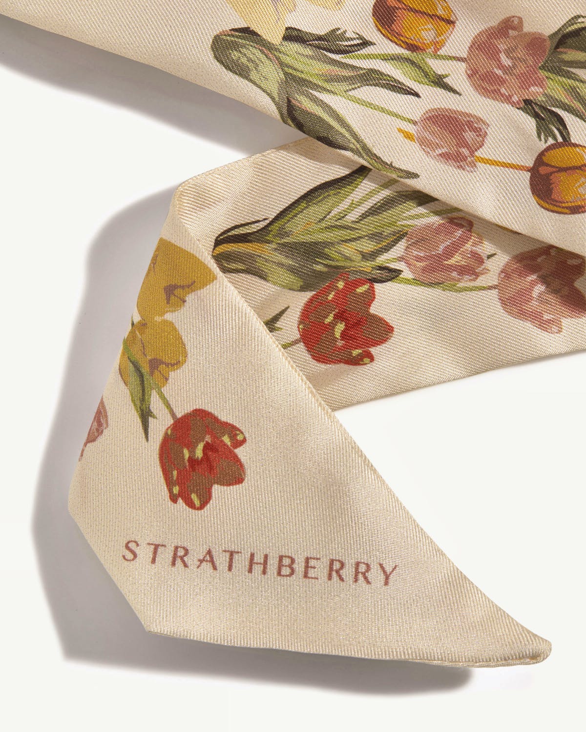 Silk skinny scarf in vanilla with tulip print and Strathberry logo visible.