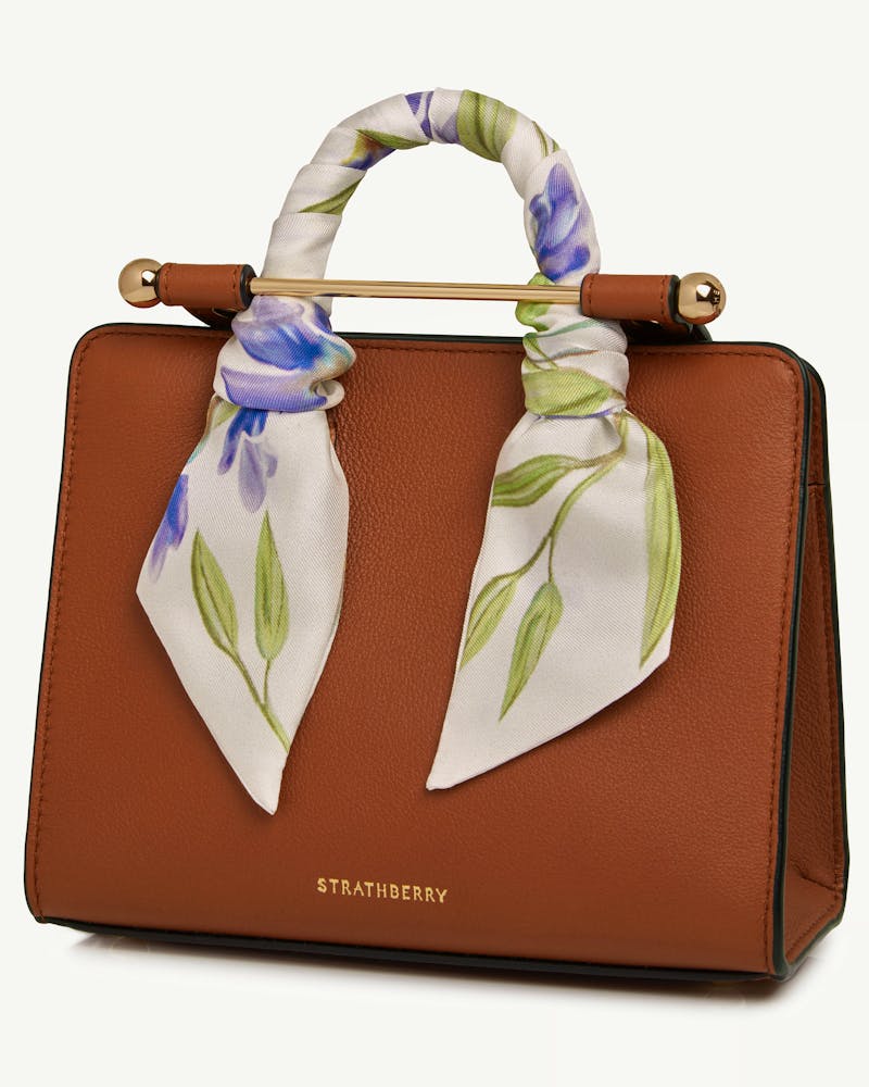 Vanilla and true blue watercolour silk skinny scarf wrapped around tan leather Strathberry handbag handle.