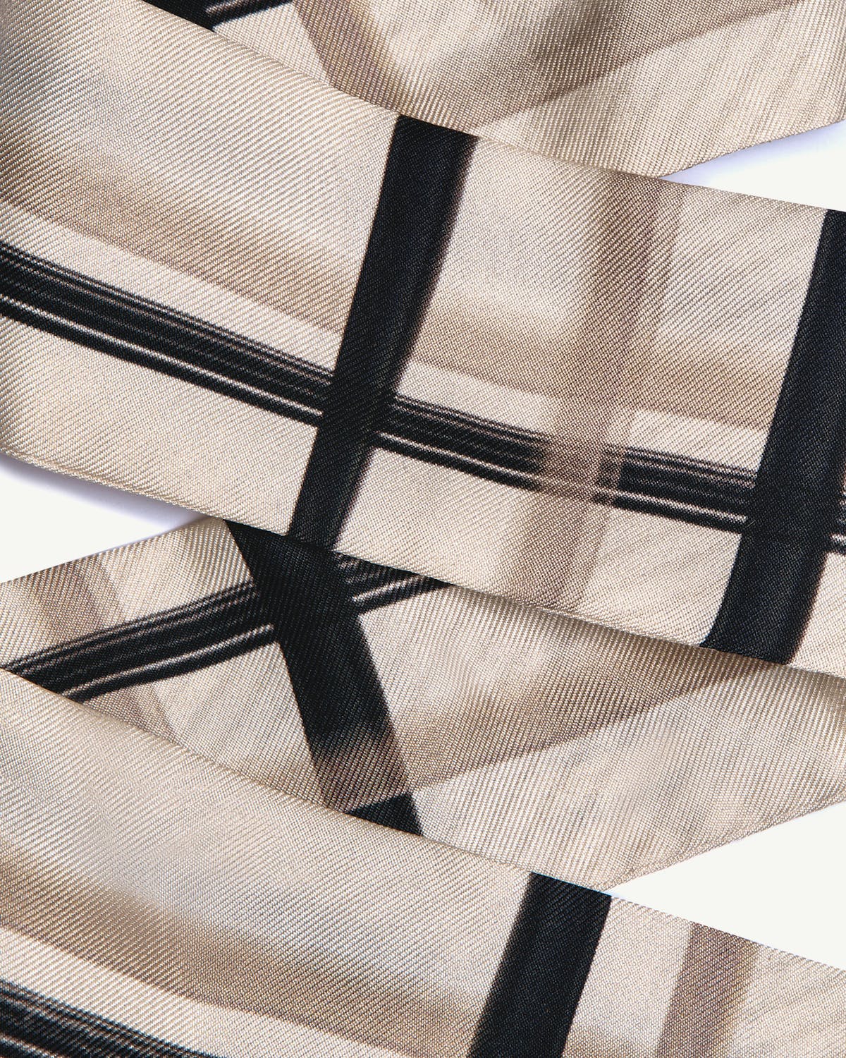 Close-up of sand and vanilla tartan silk skinny scarf showing woven texture and pattern.